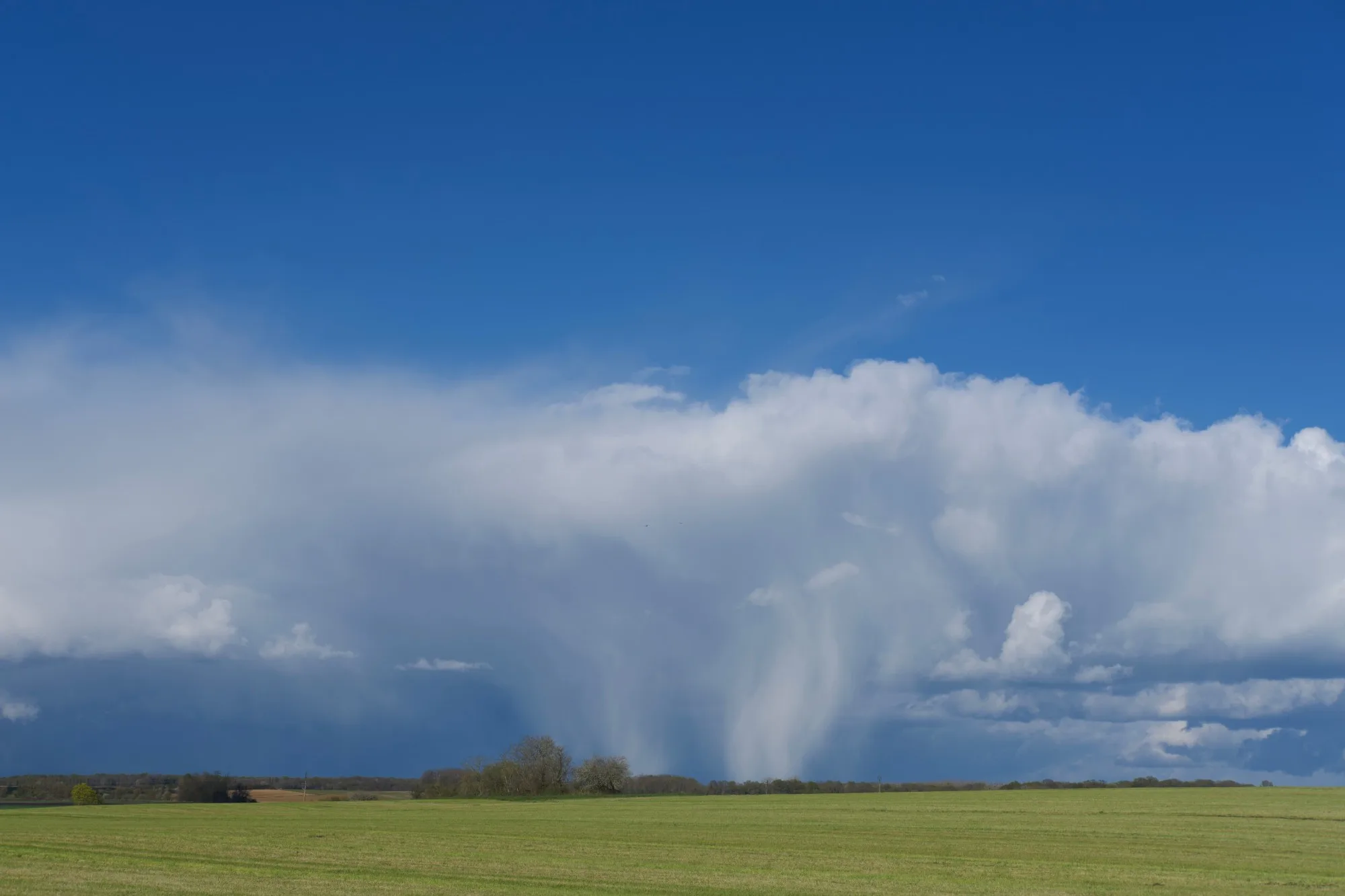 Une averse tombe d’un grand nuage au-dessus des champs