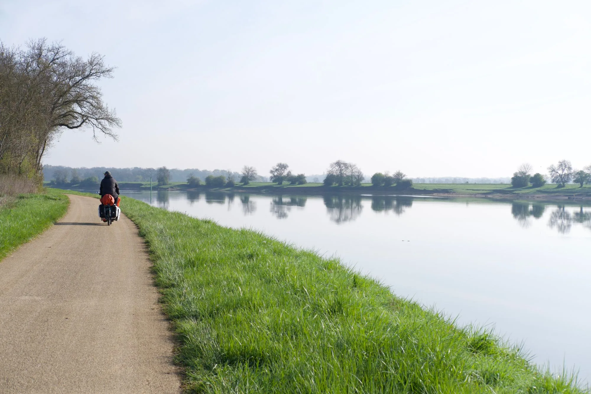 Un cycliste chargé de sacoches sur le chemin de halage, le long de la Saône